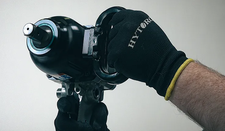 Gloved hands holding the HYTORC Pneumatic Impact Wrench using its safety handle