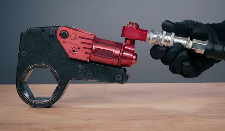 A gloved hand holds the Uniswivel connectors of the HYTORC XLCT